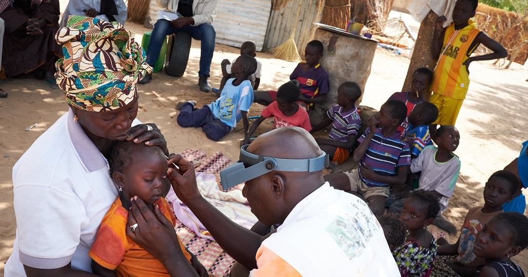 Optiker untersucht kleines Kind auf Trachome (Senegal)